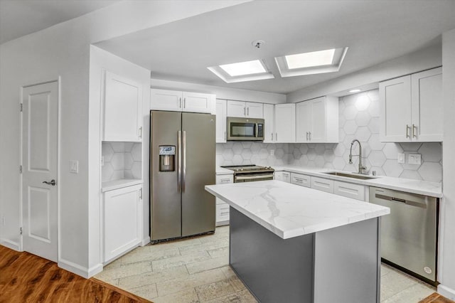 kitchen featuring a center island, a skylight, stainless steel appliances, decorative backsplash, and sink