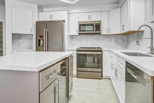 kitchen featuring appliances with stainless steel finishes, decorative backsplash, white cabinetry, and sink