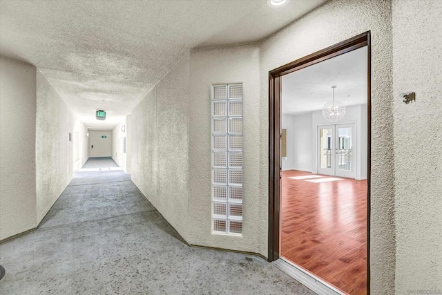 corridor with french doors and a notable chandelier