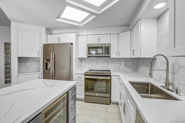 kitchen with white cabinetry, appliances with stainless steel finishes, tasteful backsplash, beverage cooler, and sink