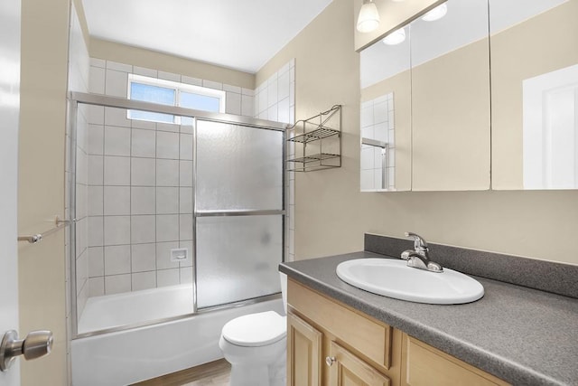 full bathroom with toilet, combined bath / shower with glass door, hardwood / wood-style flooring, and vanity