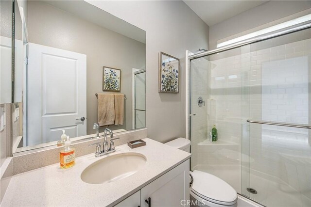 bathroom featuring toilet, walk in shower, and vanity