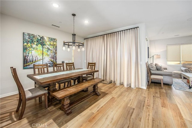 dining space featuring light hardwood / wood-style flooring and a chandelier