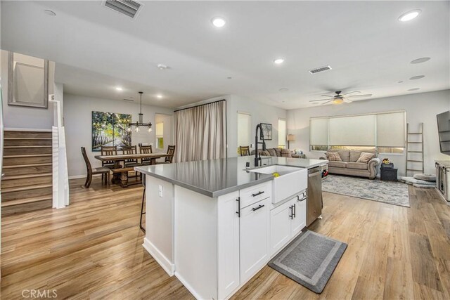 kitchen with white cabinetry, a center island with sink, ceiling fan, dishwasher, and pendant lighting