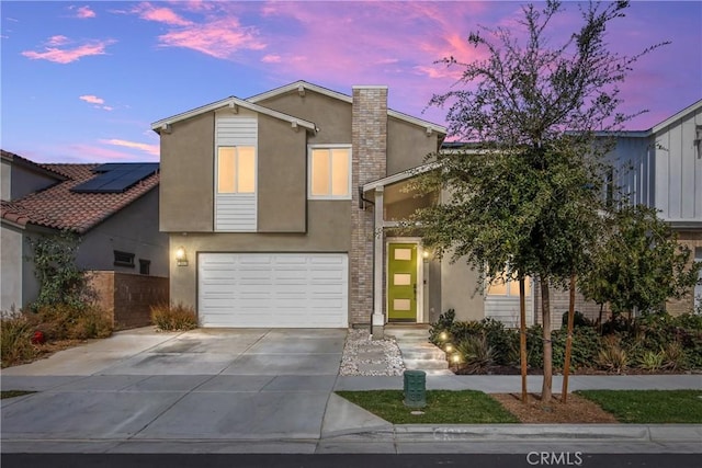 view of front of house featuring a garage, concrete driveway, and stucco siding