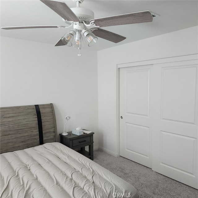 carpeted bedroom featuring ceiling fan and a closet