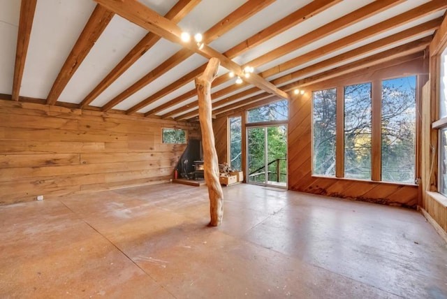 interior space featuring concrete floors, wood walls, and lofted ceiling with beams