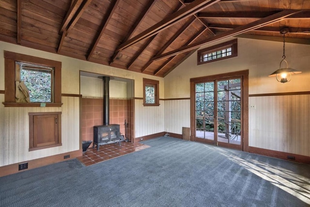 unfurnished living room featuring dark colored carpet, wooden ceiling, a wood stove, and vaulted ceiling with beams