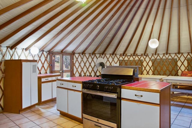 kitchen with tile countertops, gas stove, lofted ceiling with beams, light tile patterned floors, and white cabinets