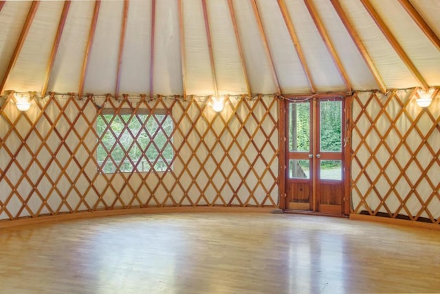 unfurnished living room with light wood-type flooring and lofted ceiling with beams