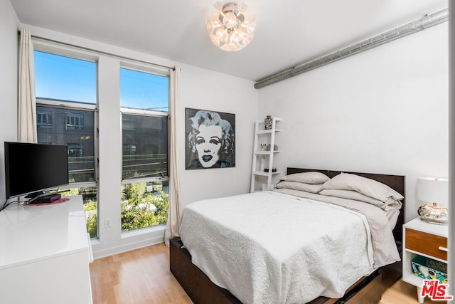 bedroom featuring an inviting chandelier and light hardwood / wood-style flooring