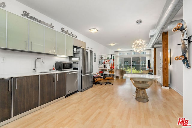 kitchen featuring appliances with stainless steel finishes, decorative light fixtures, sink, light wood-type flooring, and green cabinets