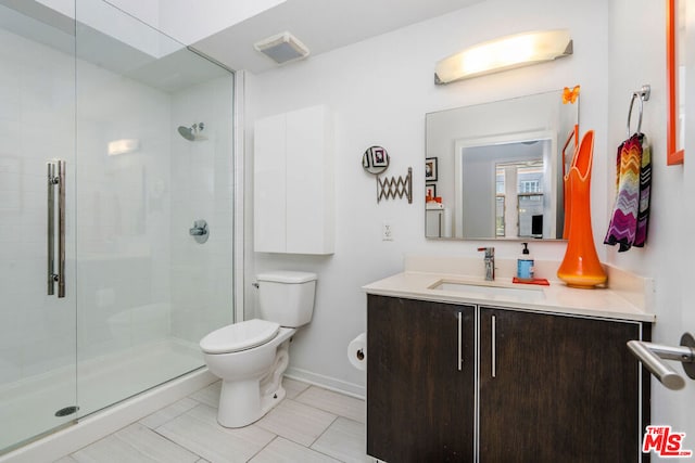 bathroom featuring toilet, vanity, and a shower with door