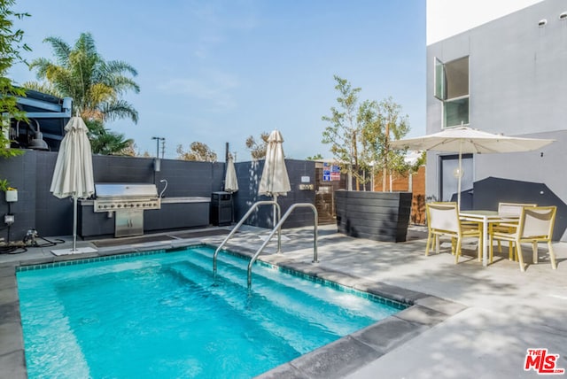 view of pool with a grill, an outdoor kitchen, and a patio