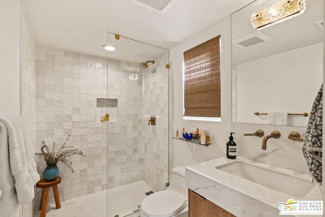 bathroom with toilet, tiled shower, and vanity