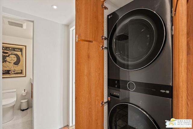 laundry area featuring stacked washer / drying machine and tile patterned floors