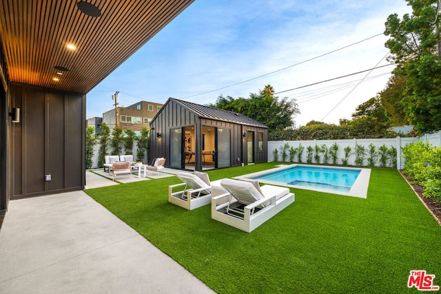 view of pool with a patio area, an outbuilding, an outdoor living space, and a yard