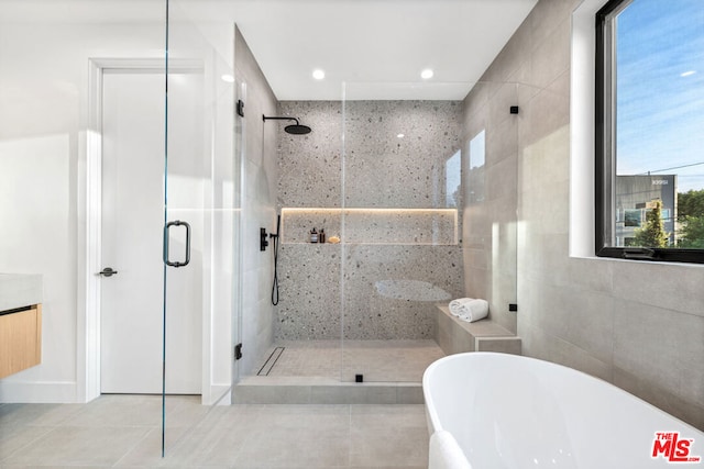 bathroom featuring vanity, tile walls, tile patterned floors, and shower with separate bathtub