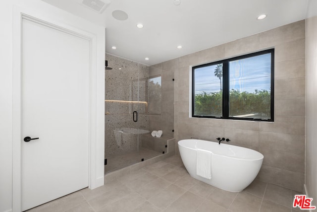 bathroom featuring independent shower and bath, tile patterned flooring, and tile walls