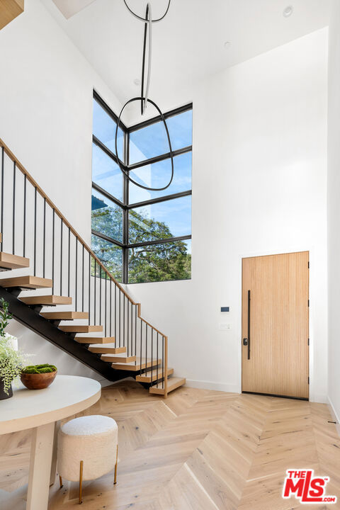 foyer with light parquet floors and a towering ceiling