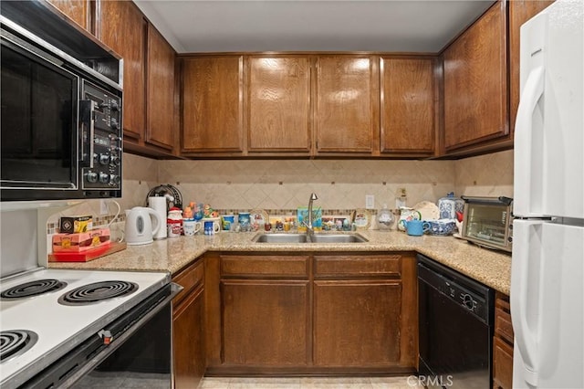 kitchen featuring sink, backsplash, black appliances, and light stone countertops