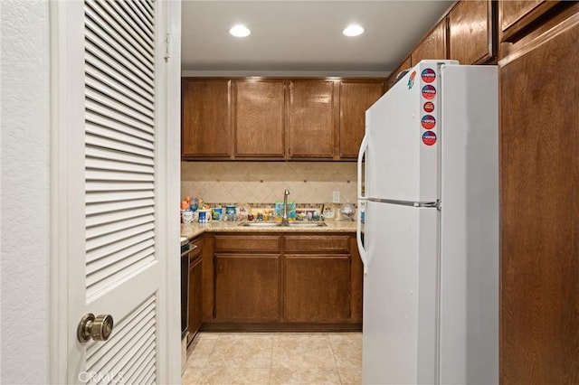 kitchen with electric stove, light tile patterned floors, white refrigerator, sink, and backsplash