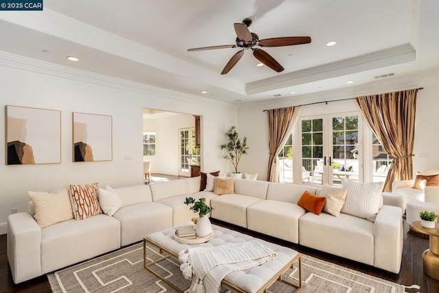 living room featuring wood-type flooring, french doors, a raised ceiling, ceiling fan, and crown molding