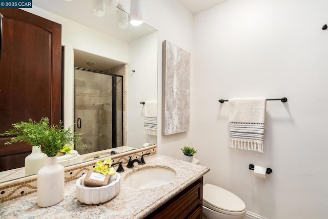 bathroom featuring a shower with shower door, vanity, and toilet