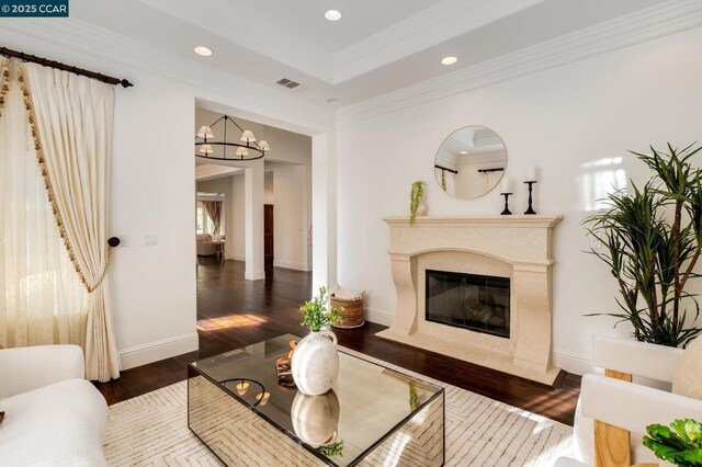 living room featuring a tray ceiling, dark hardwood / wood-style floors, a high end fireplace, and crown molding