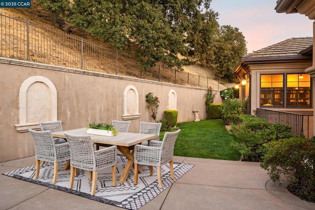 patio terrace at dusk featuring a yard