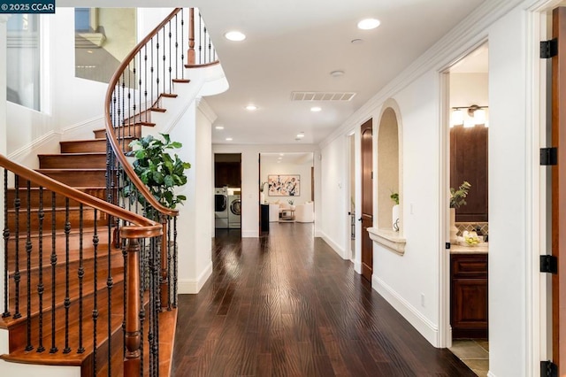 hallway with separate washer and dryer, ornamental molding, and hardwood / wood-style flooring