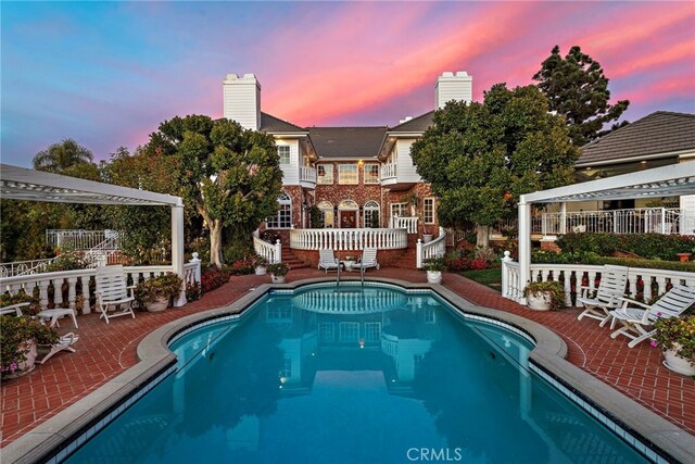 pool at dusk featuring a patio