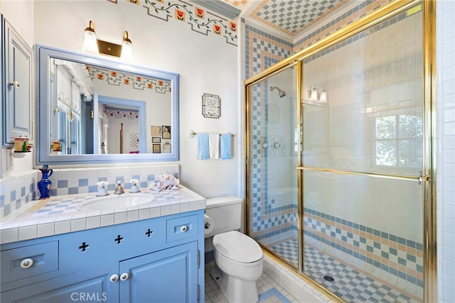 bathroom featuring toilet, vanity, tile patterned flooring, decorative backsplash, and a shower with door