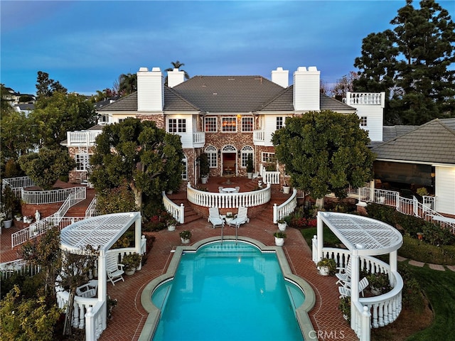 rear view of house with a fenced in pool