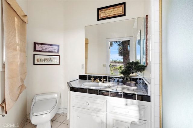 bathroom with toilet, vanity, and tile patterned flooring