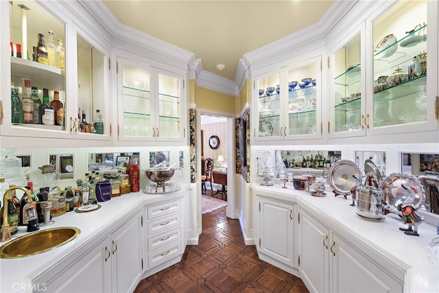 bar featuring sink, white cabinetry, and ornamental molding