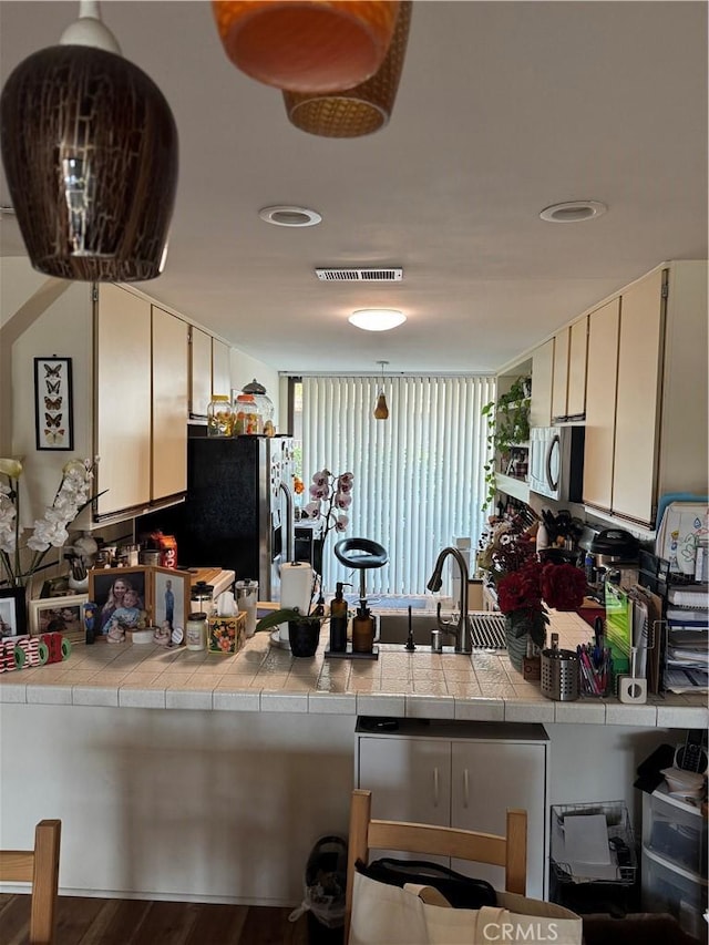 kitchen featuring tile counters, sink, dark wood-type flooring, and appliances with stainless steel finishes