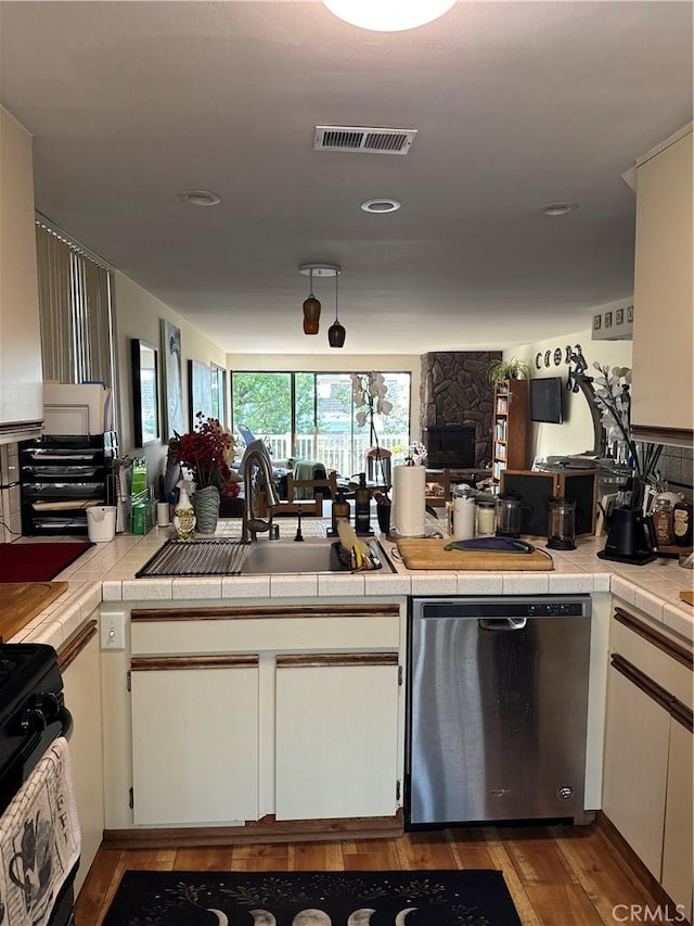 kitchen featuring dishwasher, black gas range, sink, tile counters, and wood-type flooring