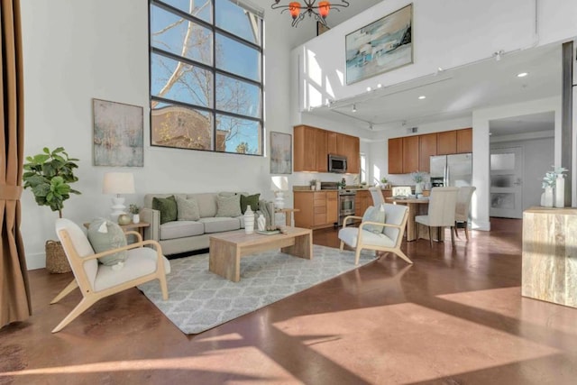 living room with a high ceiling, concrete floors, and a notable chandelier