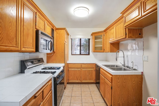 kitchen featuring sink, dishwasher, light tile patterned flooring, decorative backsplash, and white range oven