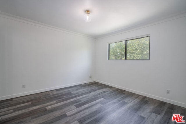 spare room featuring ornamental molding and dark hardwood / wood-style floors