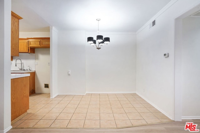 unfurnished dining area with light tile patterned flooring, crown molding, a chandelier, and sink