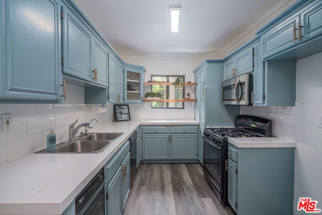 kitchen with ornamental molding, black appliances, tasteful backsplash, and sink