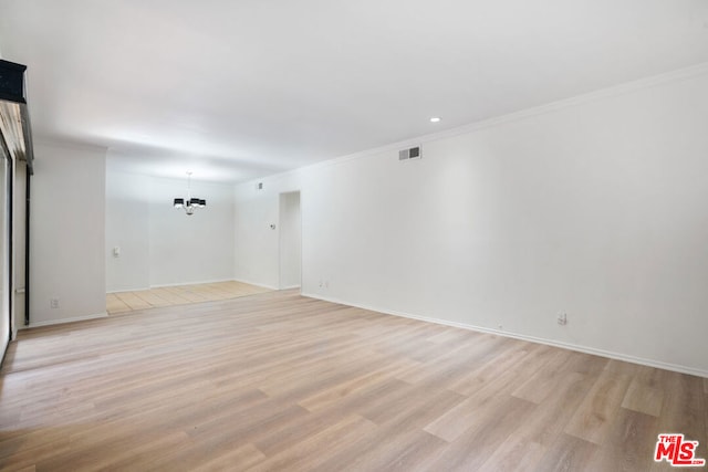 unfurnished room with an inviting chandelier, light hardwood / wood-style floors, and crown molding