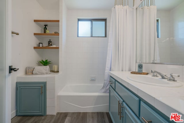 bathroom with shower / bathtub combination with curtain, wood-type flooring, and vanity