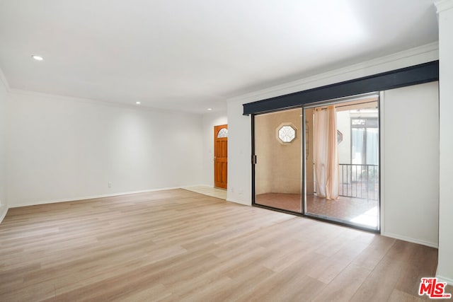 spare room featuring light wood-type flooring and crown molding