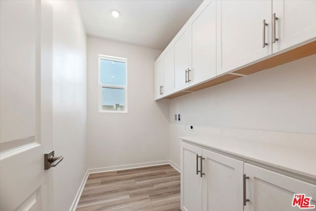 washroom featuring cabinets, electric dryer hookup, hookup for a washing machine, and light hardwood / wood-style floors