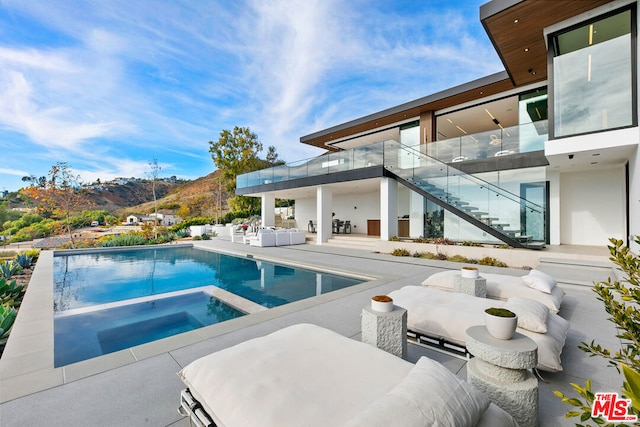 view of pool with an outdoor living space, a patio area, a mountain view, and an in ground hot tub