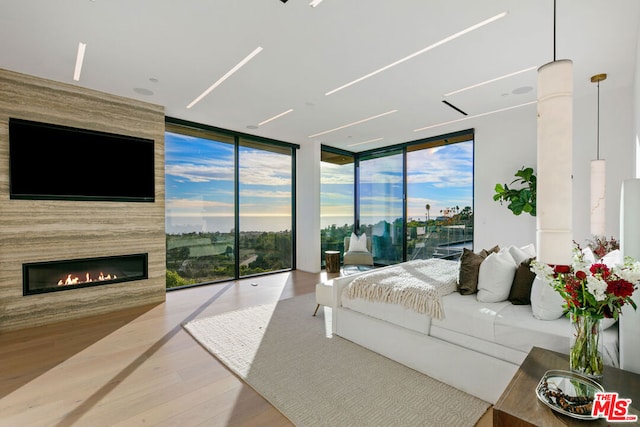 bedroom with a large fireplace, a wall of windows, access to outside, and hardwood / wood-style floors