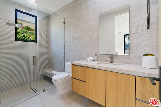 bathroom with an enclosed shower, tile patterned floors, vanity, tile walls, and toilet